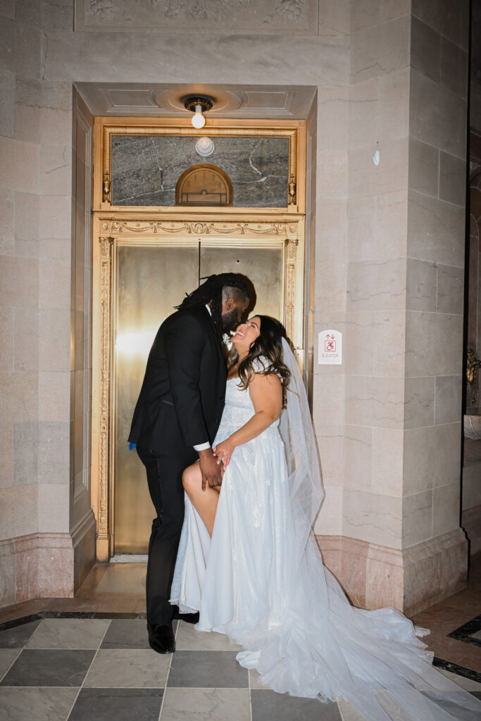 A bride and groom kiss by the gold elevators at their Hartford City Hall elopement, in Hartford CT
