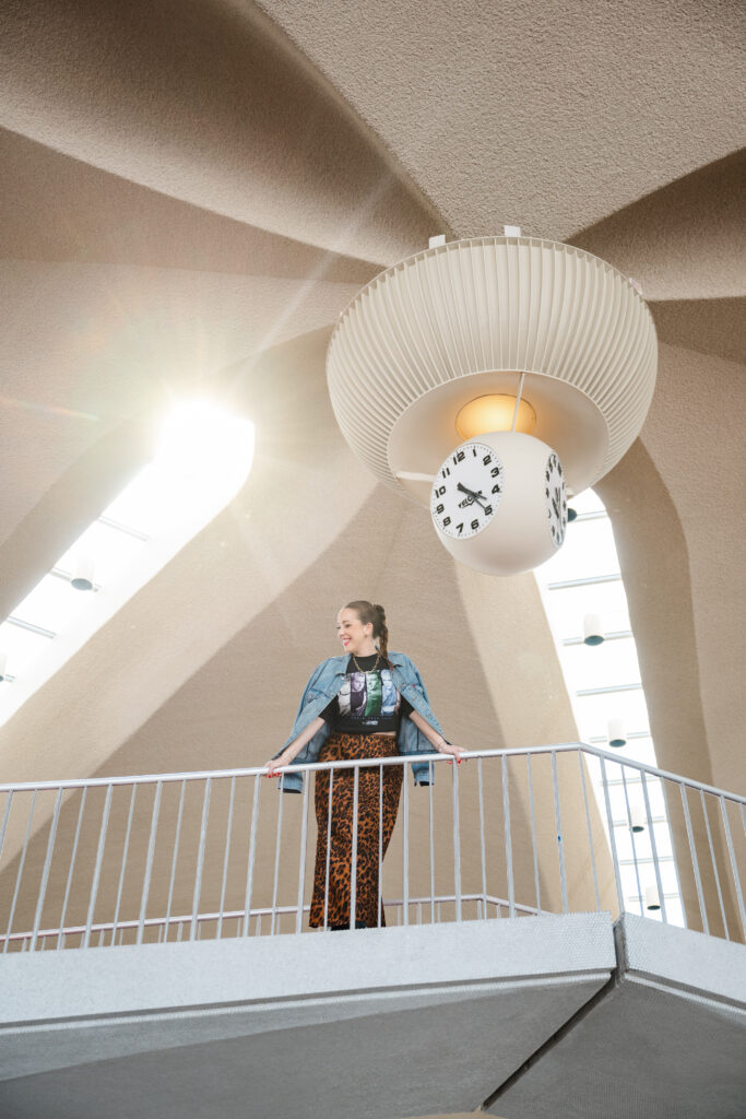 Carla Giorgio poses for her on location branding photos near the iconic clock inside the TWA Hotel in NYC