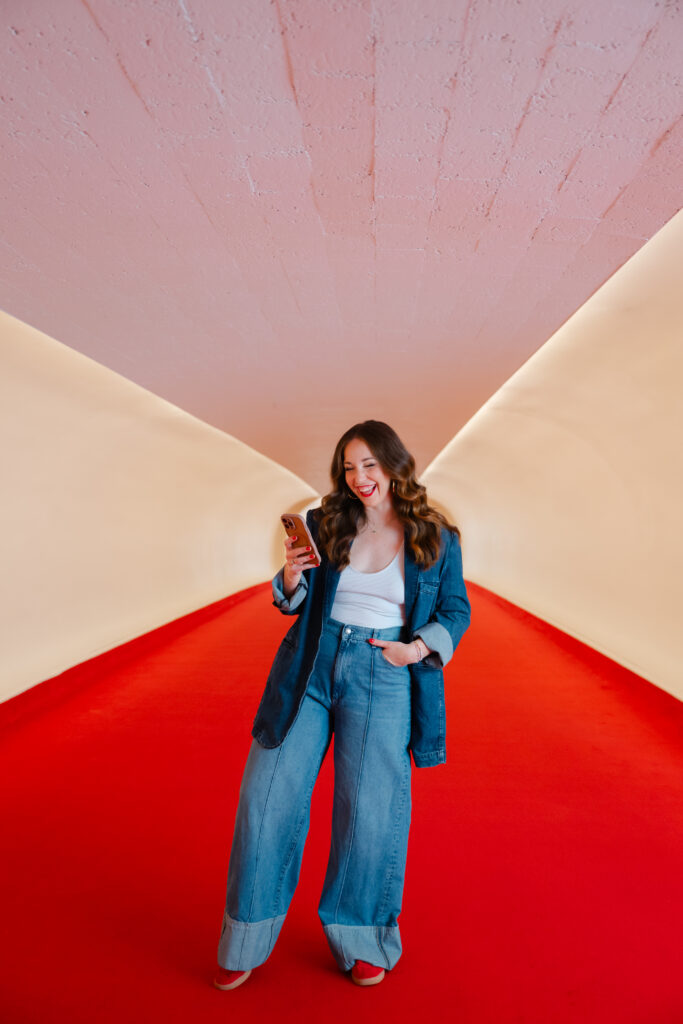 Wide shot of Carla Giorgio walking through the retro red carpet hallway of the TWA Hotel for her NYC branding shoot