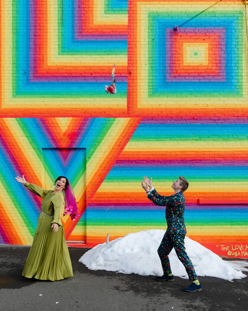 Two brides on their colorful Hartford City Hall elopement in front of a rainbow mural in Hartford CT
