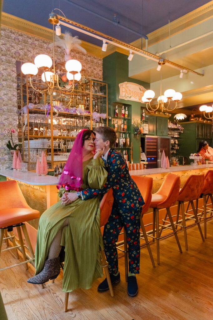Two brides pose for photos before their colorful Hartford City Hall elopement at the Hartford Flavor Cocktail Parlour on Pratt Street