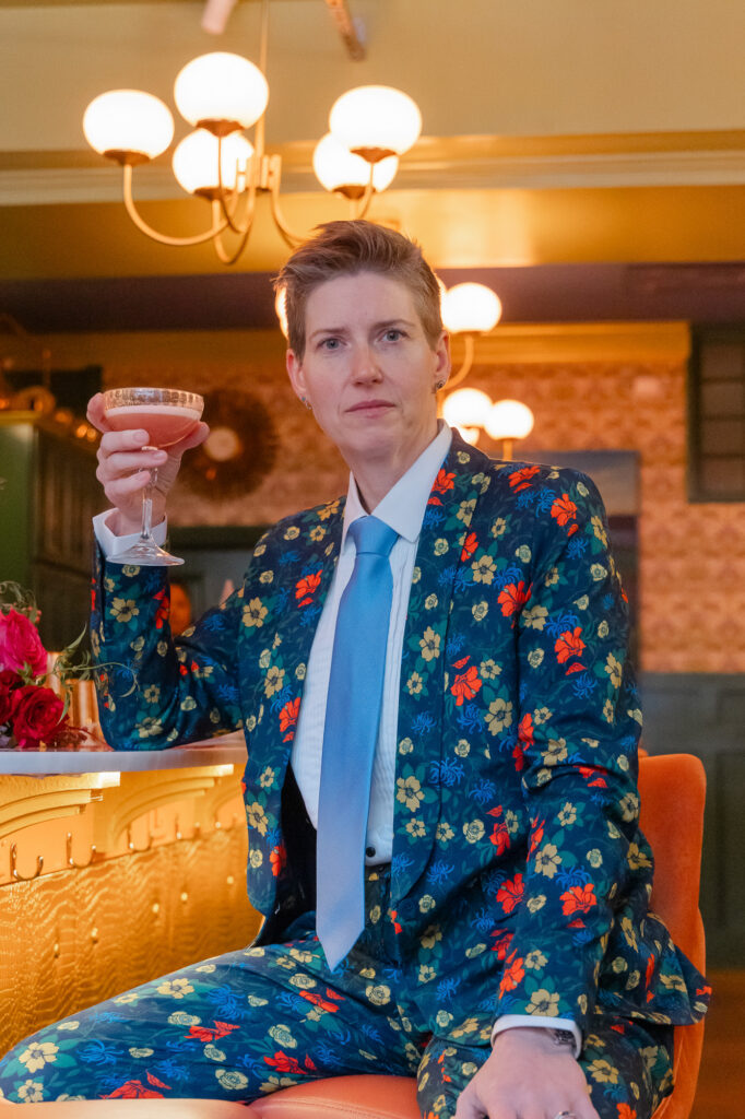 A colorful queer bride pose with her cocktail at the Hartford Flavor Cocktail Parlour before her Hartford City Hall elopement