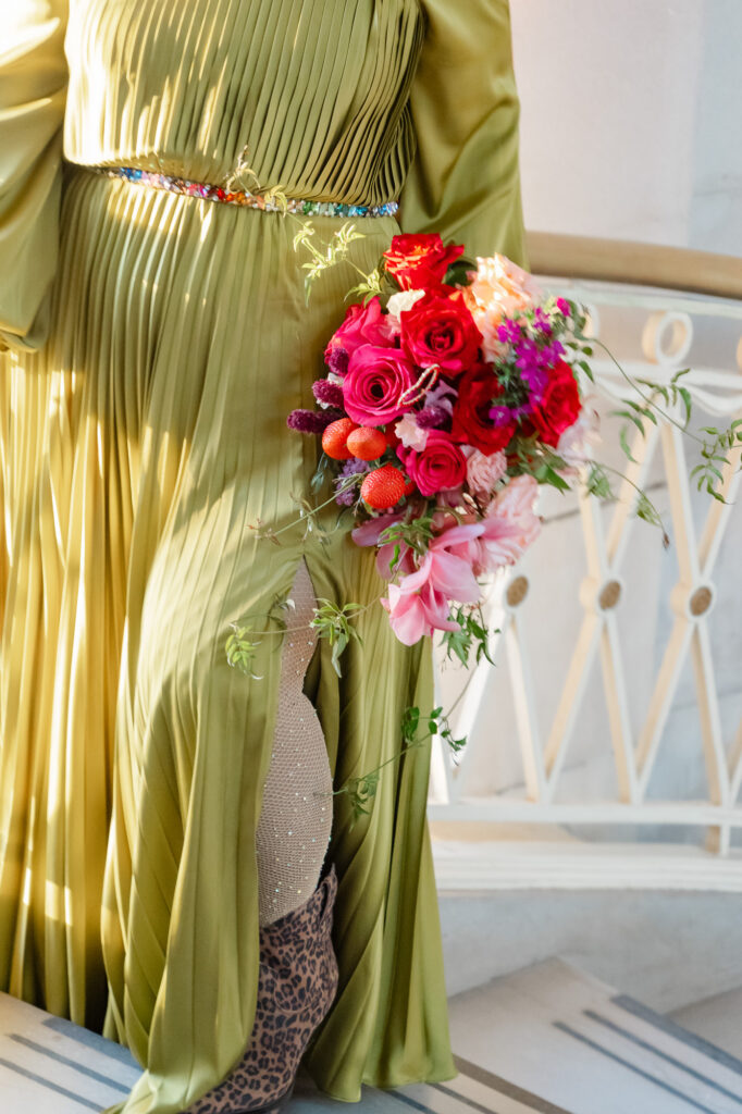 A queer bride poses with her sparkly fishnet tights, leopard booties, chartreuse wedding dress and colorful wedding bouquet with strawberries in it at her Hartford city hall elopement