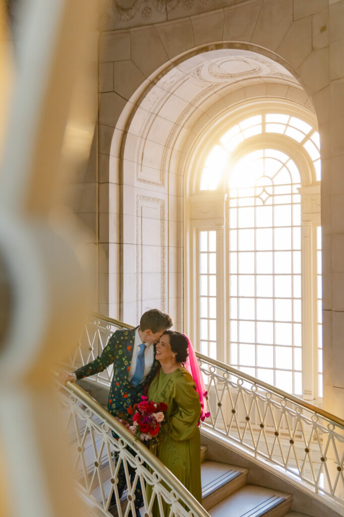 Two brides laugh during photos at their colorful Hartford City Hall elopement