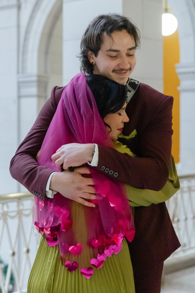 LGBTQ colorful Hartford City Hall elopement bride hugs her son in hot pink heart veil by Madison Chamberlain