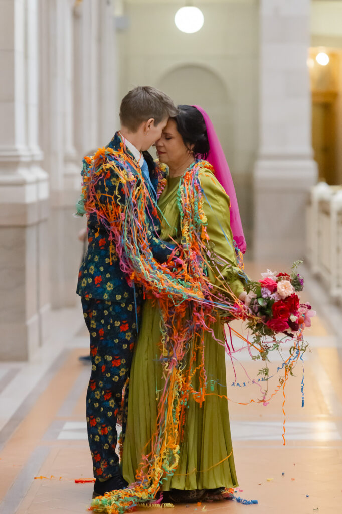 Two brides dance covered in colorful streamers at their Hartford City Hall elopement