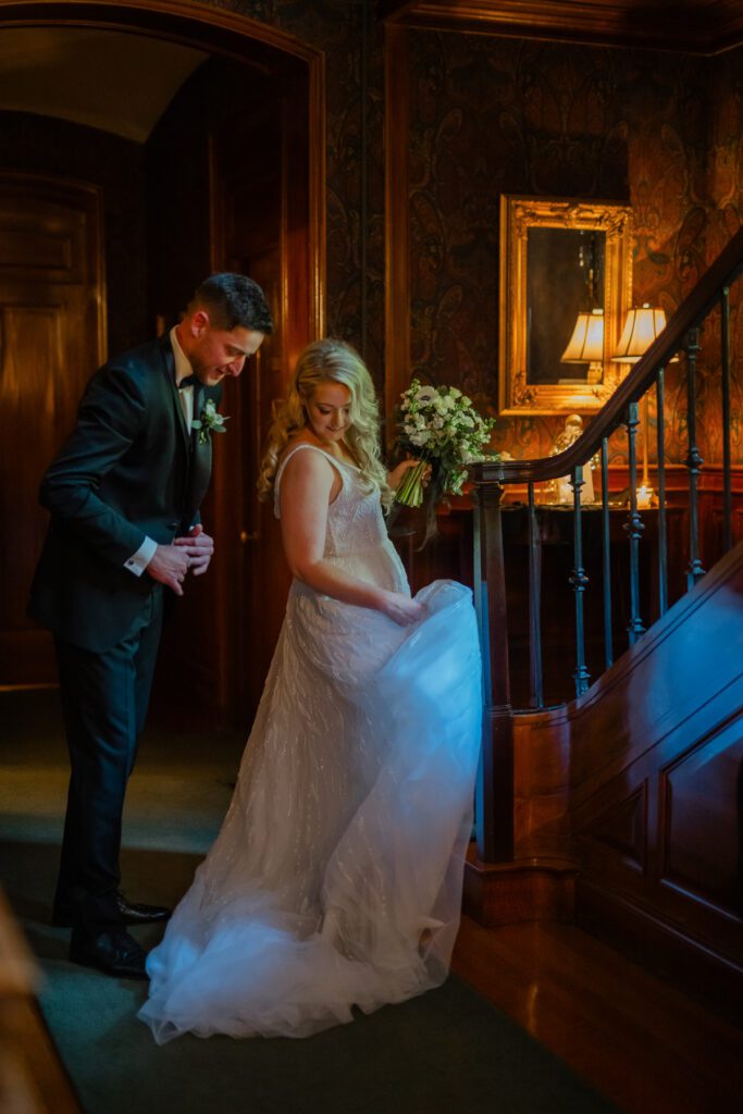Lord Thompson Manor wedding photographer catches a moment between a bride and groom as they make their way inside the manor by the staircase at their Lord Thompson Manor wedding