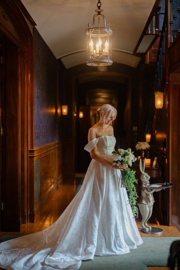 Lord Thompson Manor wedding photographer creates a portrait of a bride as she stands in the light by the front door of the manor at her Lord Thompson Manor wedding