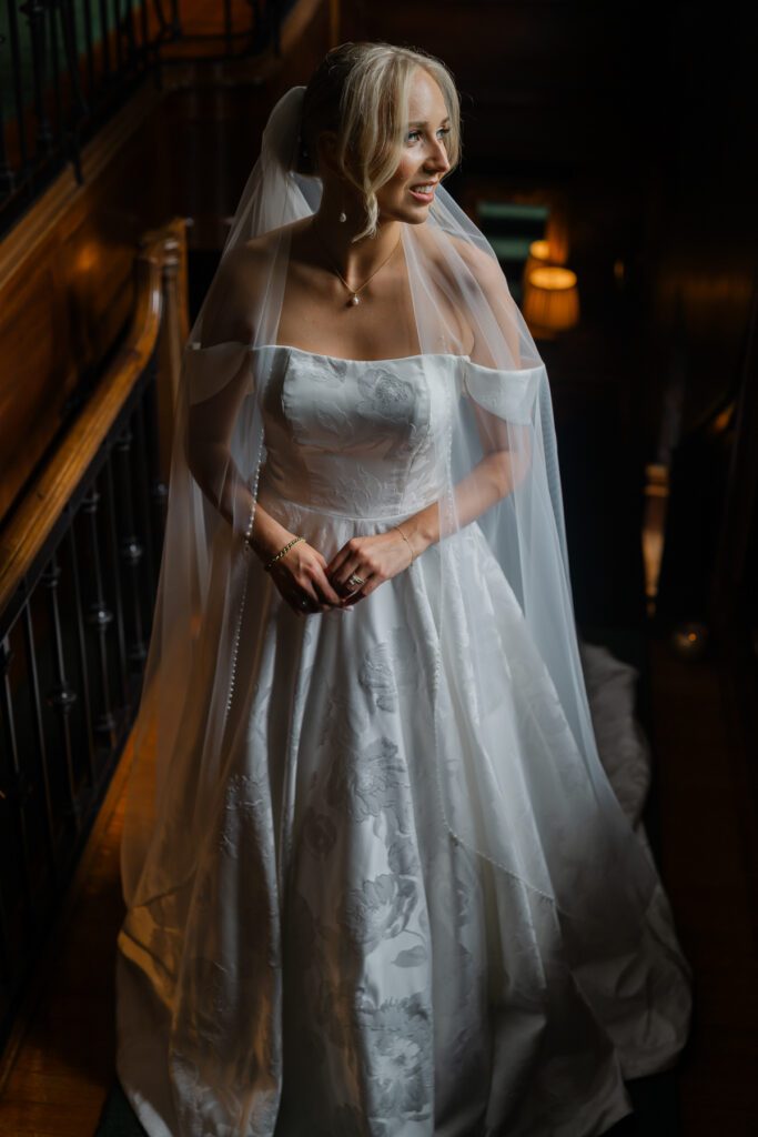 Lord Thompson Manor wedding photographer photographs a bride as she stands in the soft afternoon light on the staircase in Lord Thompson Manor on her wedding day.