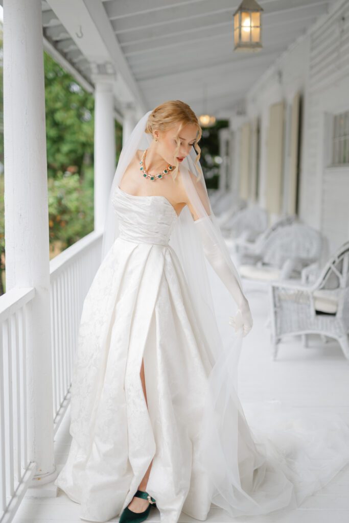 Lord Thompson Manor wedding photographer photographs a bride as she fixes her wedding gown at the Cottage at her Lord Thompson Manor wedding in Thompson CT